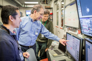 Nicholas Saute pointing to a monitor during an experiment at SLAC