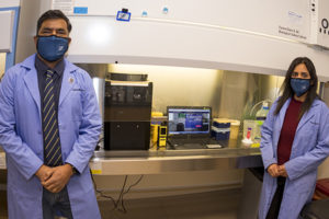 Subhash Verma, Ph.D., associate professor of microbiology and immunology (left) and Timsy Uppal, Ph.D., research scientist, department of microbiology and immunology (right) pose with a dry-sanitizing device.