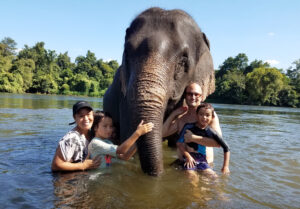 Dylan Chivian and family pose with an elephant while bathing in a river.
