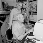 Black and white photo of two men, Melvin Klein and Kenneth Sauer, working together behind a computer.