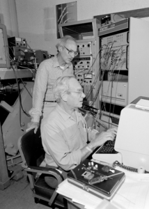 Black and white photo of two men, Melvin Klein and Kenneth Sauer, working together behind a computer.