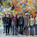 A group of ASU students pose with their Berkeley Lab mentors in front of the JGI mural.