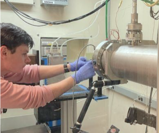 Photo of a graduate student wearing gloves and concentrating as they calibrate equipment.