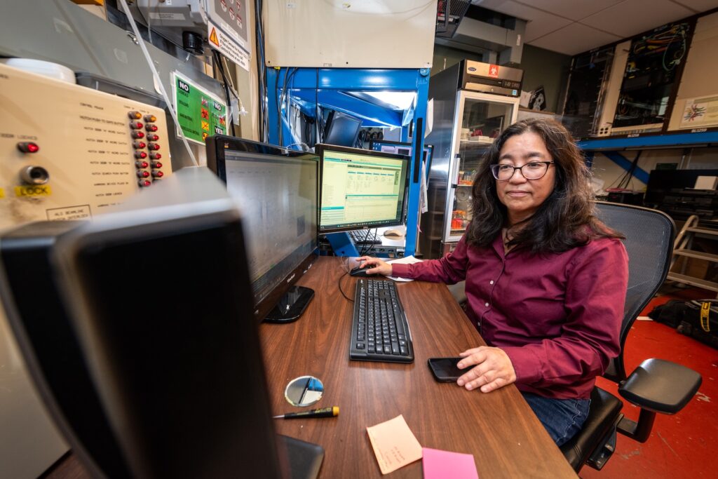 Researcher Susan Tsutakawa smiles as she sits at her computer desk.