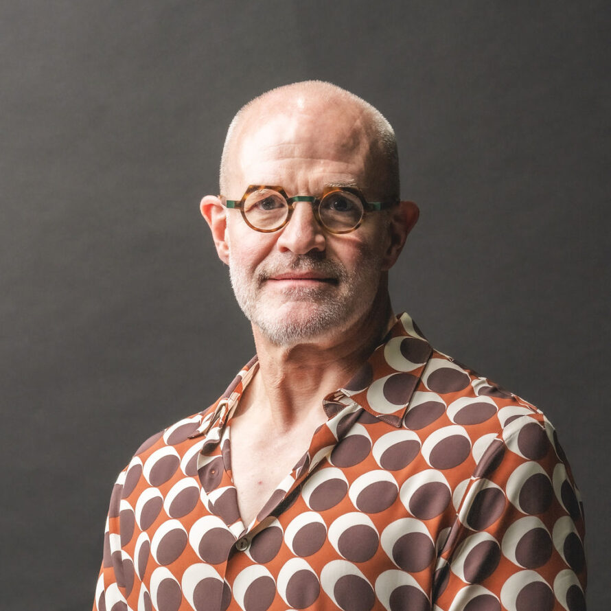 Jay Keasling, a bald man with a grey beard, wearing brown framed glasses and an orange shirt with white and brown circles