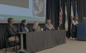 Group of four panelists on stage with moderator off to the right side.