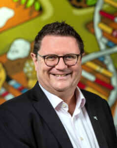 Headshot of Nigel Mouncey with colorful background