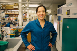researcher standing with hands on hips with lab in the background